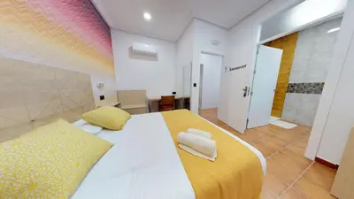 a bedroom with a large bed with a yellow and white blanket at Hostal Boutique La Española in Rota