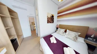 a bedroom with a large bed and a desk at Hostal Boutique La Española in Rota