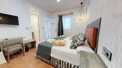 a bedroom with a bed and a desk and a television at Hostal Boutique La Española in Rota