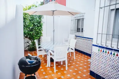 a patio with a table and chairs and an umbrella at Casa Cordoba in Chipiona