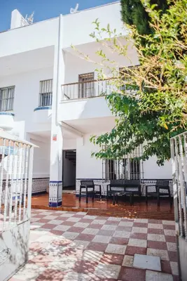 a courtyard with benches in front of a white building at Casa Cordoba in Chipiona
