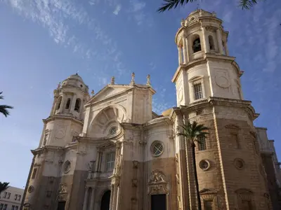 a church with two towers and a palm tree in front at Catedral Cadiz in Cádiz