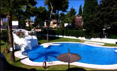 a large swimming pool with an umbrella in a yard at Apartamento Vistahermosa Centro in El Puerto de Santa María