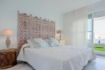 a bedroom with two beds and a nightstand and two pictures at Casas Fuente del Sol in Conil de la Frontera