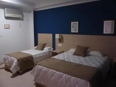 a hotel room with two beds and a blue wall at Hotel Catalán Puerto Real in Puerto Real