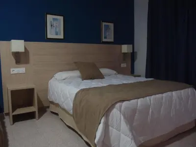 a bedroom with a large bed with a blue wall at Hotel Catalán Puerto Real in Puerto Real