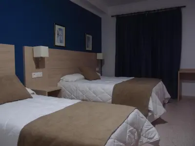 two beds in a hotel room with blue walls at Hotel Catalán Puerto Real in Puerto Real