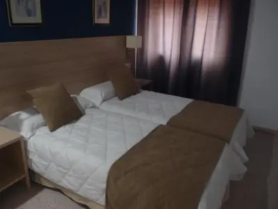 a bedroom with a large bed with white sheets at Hotel Catalán Puerto Real in Puerto Real