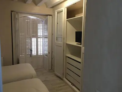 a bedroom with two beds and a tv and a closet at Casa Bugambilla Cadiz in Cádiz