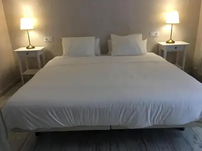 a large white bed with two lamps on both sides at Casa Bugambilla Cadiz in Cádiz