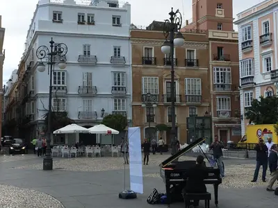 a man playing a grand piano on a city street at Casa Bugambilla Cadiz in Cádiz