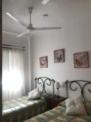 a bedroom with two beds and a ceiling fan at Tabano in Chipiona