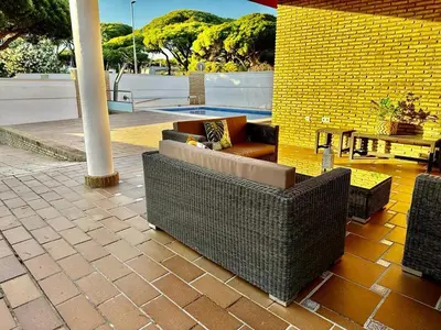 a patio with wicker chairs and tables and a pool at Chalet Nora in Chiclana de la Frontera
