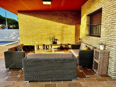 a patio with wicker furniture and a brick wall at Chalet Nora in Chiclana de la Frontera