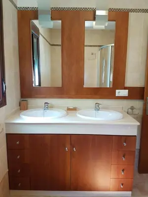 a bathroom with two sinks and two mirrors at Chalet Nora in Chiclana de la Frontera
