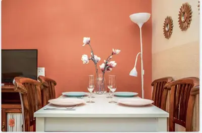 a table with plates and glasses and a vase with flowers at Piso Ribera del Marisco in El Puerto de Santa María