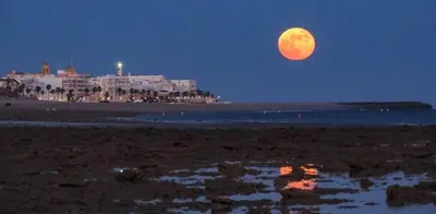 a full moon rising over a beach at night at Isabelita in Rota
