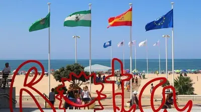 a sign on the beach with flags in the background at Isabelita in Rota