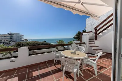 a patio with a table and chairs and the ocean at Villas Flamenco Beach Conil in Conil de la Frontera