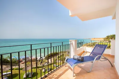a blue chair sitting on a balcony overlooking the ocean at Hipotels Flamenco Conil in Conil de la Frontera