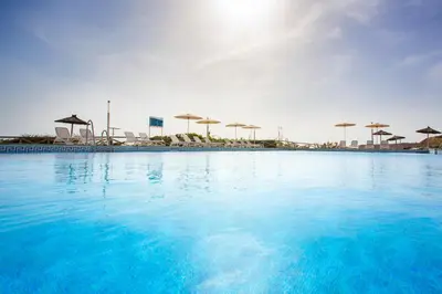 a large pool of blue water with umbrellas in the background at Hipotels Flamenco Conil in Conil de la Frontera