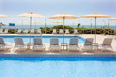 a swimming pool with chairs and umbrellas at Hipotels Flamenco Conil in Conil de la Frontera