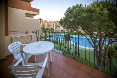 a balcony with a table and chairs and a swimming pool at Aparthotel las Dunas in Chiclana de la Frontera