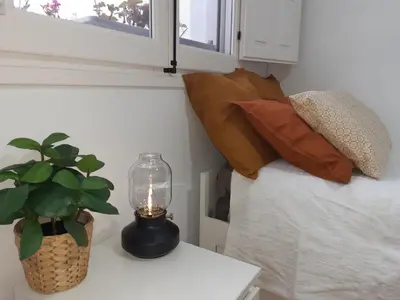 a lamp on a table next to a bed with a plant at Casa Caleta a 2 minutos de la playa in Cádiz