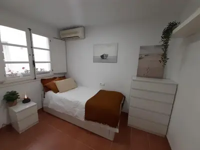 a small bedroom with a bed and two windows at Casa Caleta a 2 minutos de la playa in Cádiz