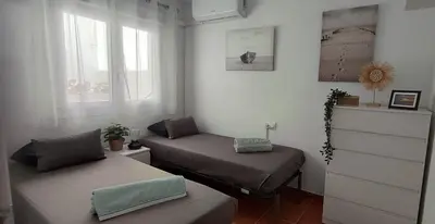 a small room with two beds and a window at Casa Caleta a 2 minutos de la playa in Cádiz