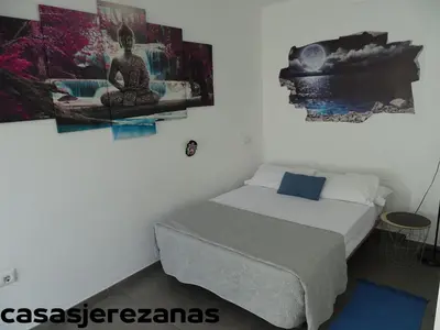a bedroom with a bed and a painting on the wall at Casasjerezanas Loft Las Flores in Jerez de la Frontera