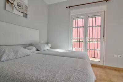 two beds in a white room with a window at Apartamentos Centro 2 el Puerto in El Puerto de Santa María