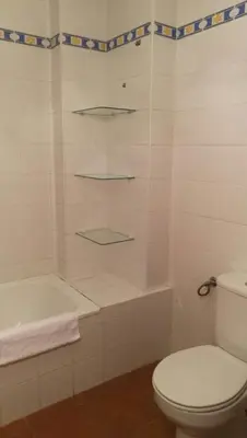 a white bathroom with a toilet and a bath tub at Apartamento Cielo 35 in El Puerto de Santa María