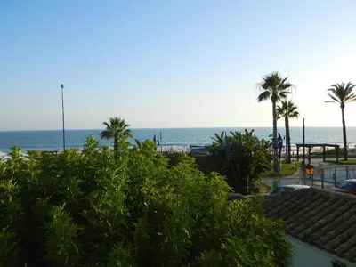 a view of the beach with palm trees and the ocean at El Campanario in Chiclana de la Frontera