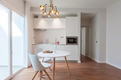 a white kitchen with a white table and chairs at Tandem Ancha 34 in Cádiz