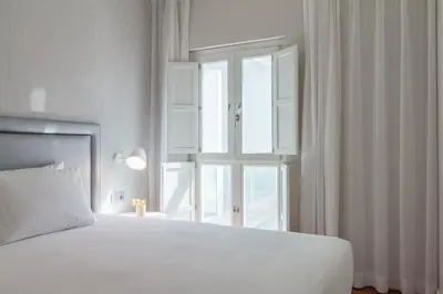 a white bedroom with a large bed and a window at Tandem Ancha 34 in Cádiz