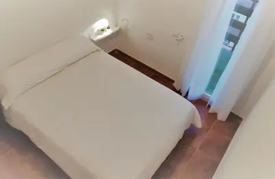 a white bed in a room with a window at El Mirador de Cadiz in Cádiz