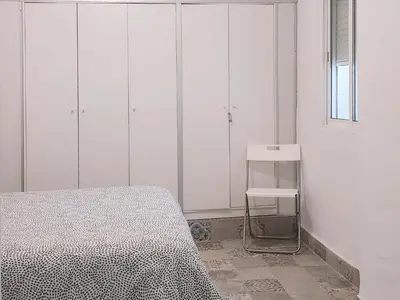 a bedroom with white cabinets and a bed and a chair at Playa de la Caleta, Cadiz in Cádiz