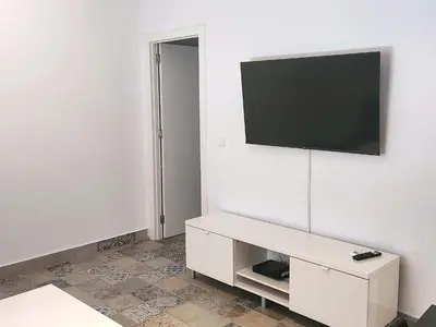 a living room with a television on a white wall at Playa de la Caleta, Cadiz in Cádiz