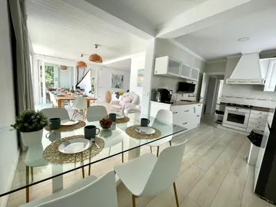 a kitchen and living room with a glass table and chairs at Chalet El Molino in Chiclana de la Frontera