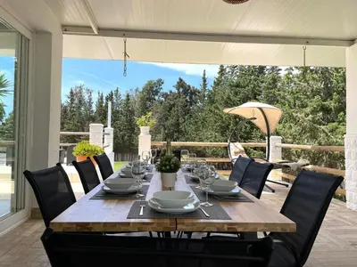 a wooden table with black chairs around it on a patio at Chalet El Molino in Chiclana de la Frontera