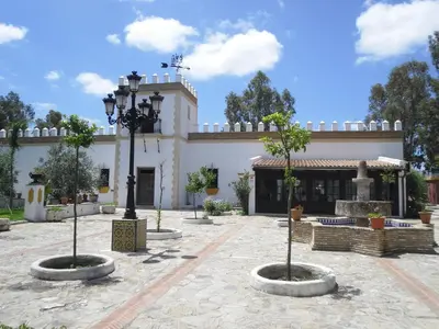 a building with a courtyard with trees in front of it at Cortijo Los Monteros in Benalup Casas Viejas