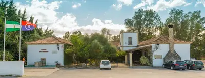 a white building with cars parked in a parking lot at Cortijo Los Monteros in Benalup Casas Viejas