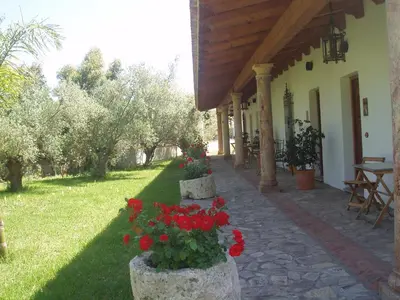 a building with two stone pillars with red flowers at Cortijo Los Monteros in Benalup Casas Viejas