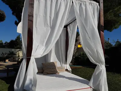 a canopy bed with white curtains in a yard at El chalet del Mar in Chiclana de la Frontera