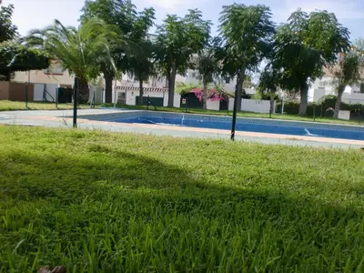 a swimming pool in a park with trees and grass at Villa Valdelagrana fantástica para familias in Cádiz