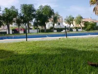 a grassy area with a pool and trees and houses at Villa Valdelagrana fantástica para familias in Cádiz