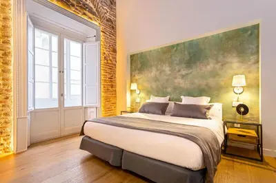 a bedroom with a large bed with a large painting on the wall at Genteel Home Plaza de España Cádiz in Cádiz