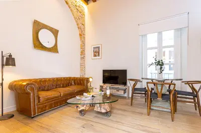 a living room with a brown leather couch and a table at Genteel Home Plaza de España Cádiz in Cádiz