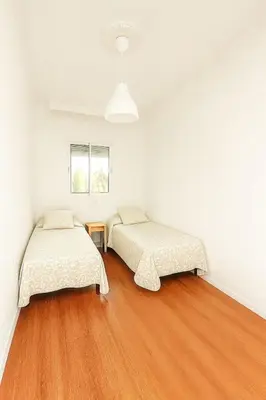 two beds in a room with white walls and wood floors at Apartamento con Vistas al González Byass in Jerez de la Frontera